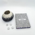 A grouping of buttons, a felt vase, and a book title 