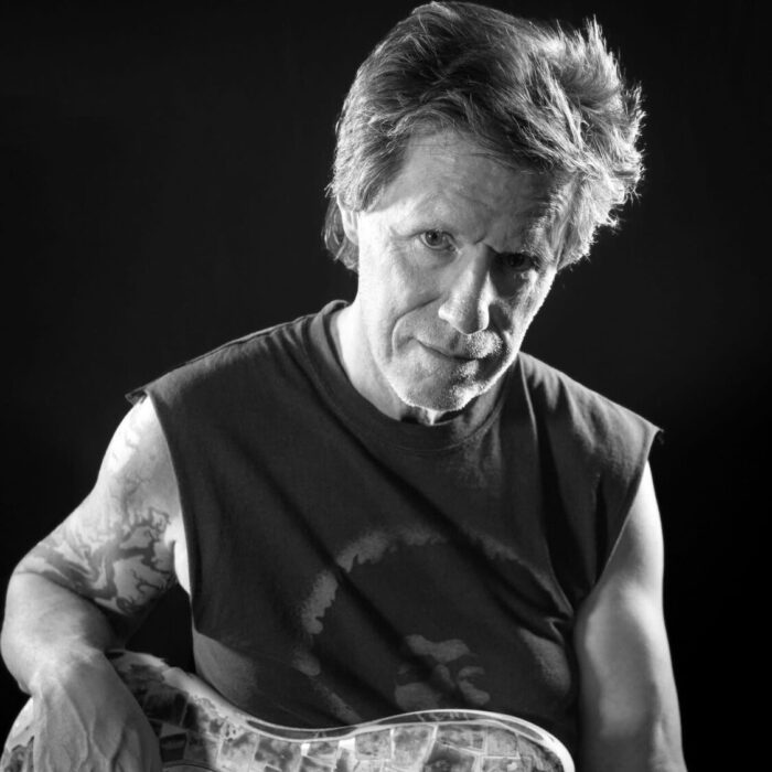 A black and white photo of a man holding a guitar.