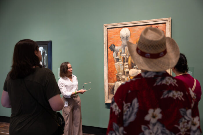 Woman explains about surrealist artwork at arts museum.