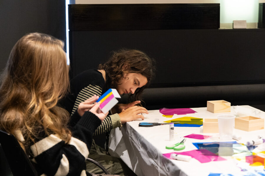 Two young women use scissors and clue to make a craft.