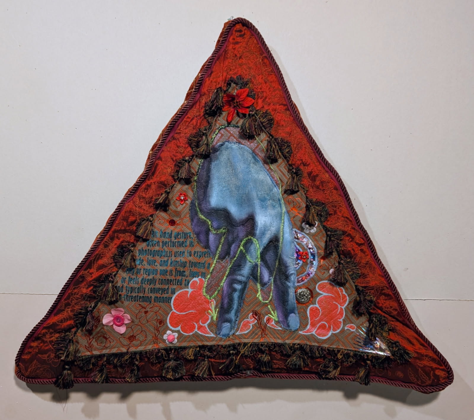 A triangle quilt with red edges and an upside-down peace sign in the middle.