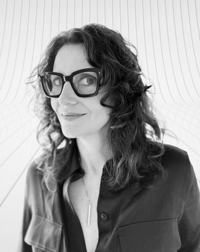 A black and white photo of a woman with think rimmed glasses. 