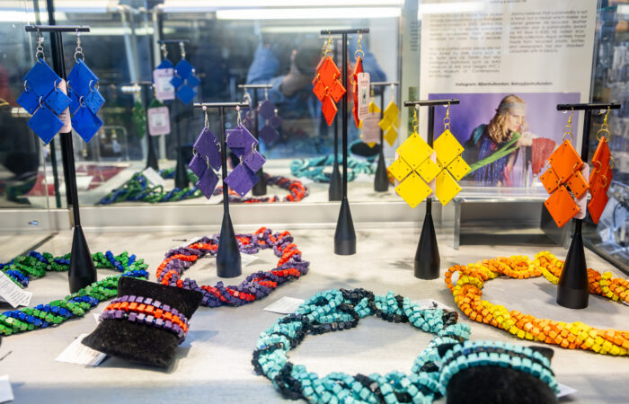 Rainbow colored jewelry displayed in a glass case.