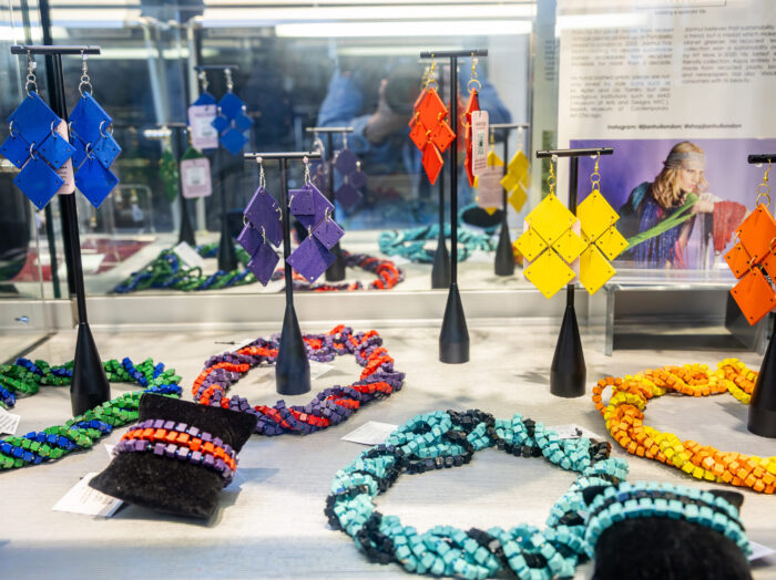 Rainbow colored jewelry displayed in a glass case.