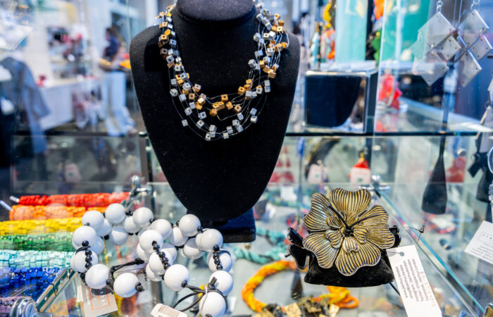 Display of beaded jewelry with accents of gold on a glass shelf.