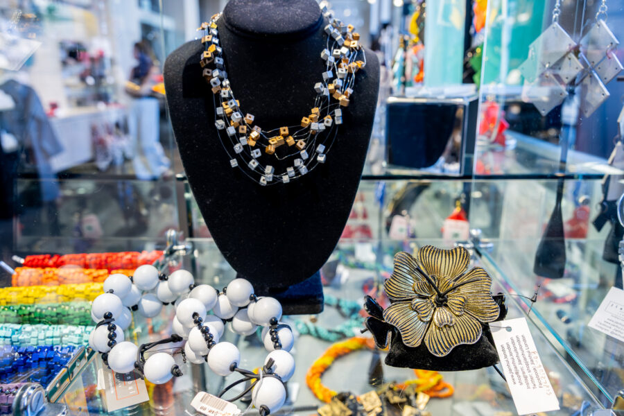 Display of beaded jewelry with accents of gold on a glass shelf.
