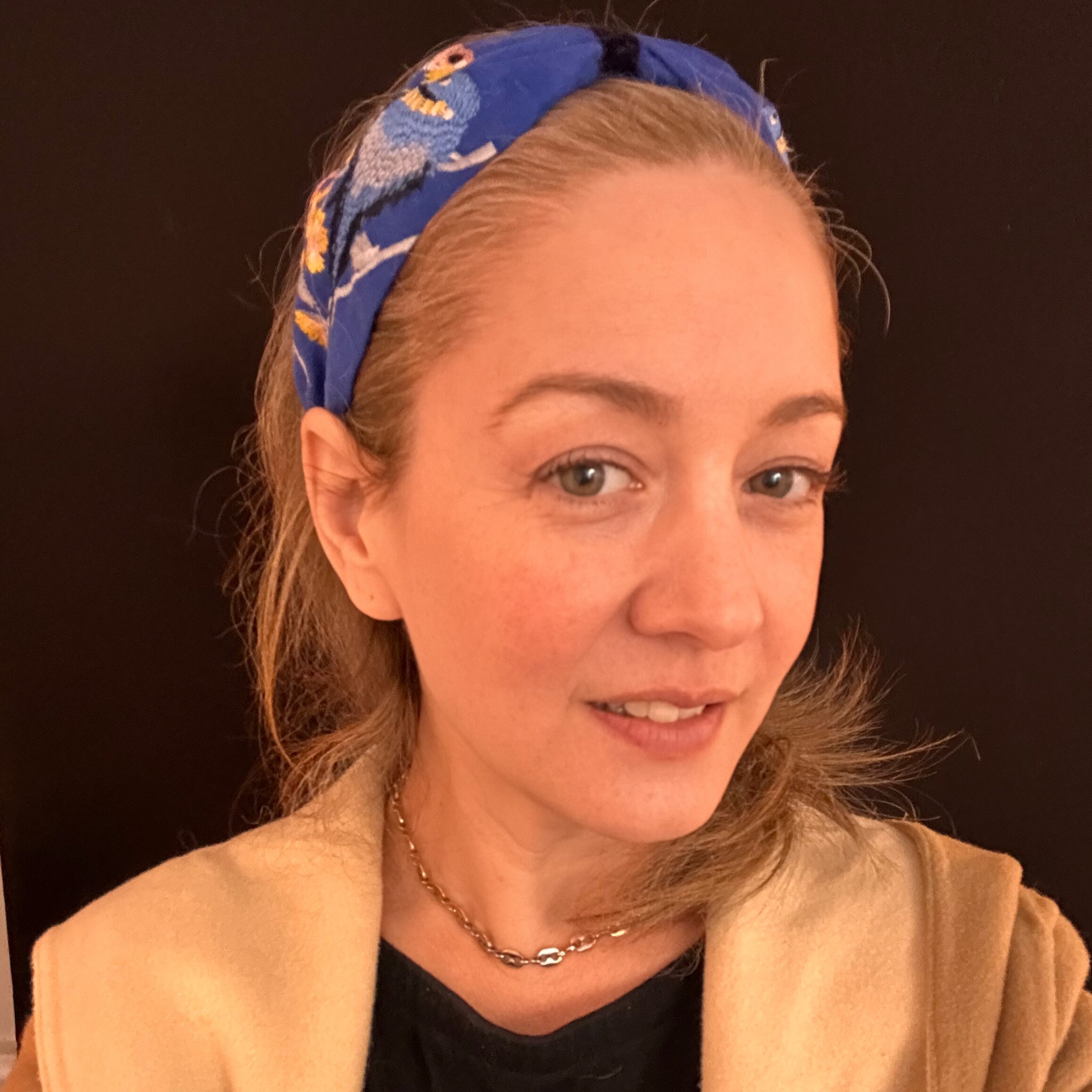 A woman poses for a selfie with a blue silk headband.