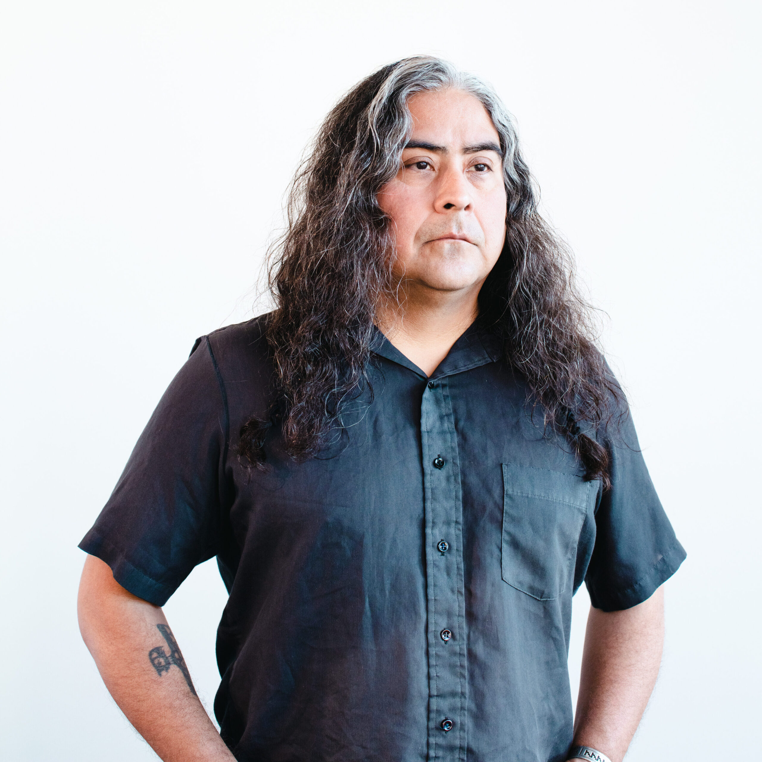 A man with long hair poses for a headshot.