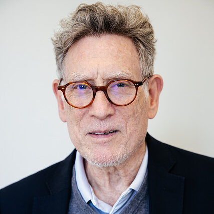 A headshot of a man with round glasses. 