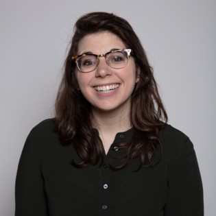 A woman with glasses smiles for a headshot.
