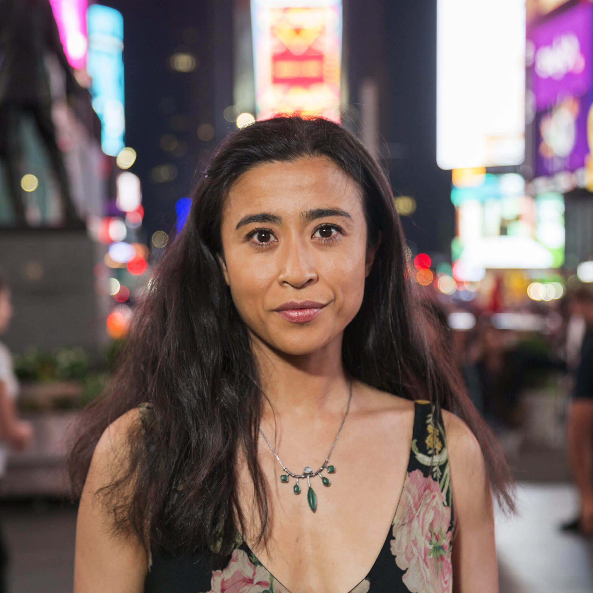 A woman stand in the middle of Time Square.