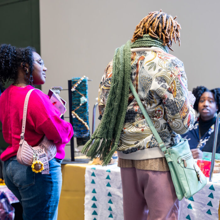 Two people shop at a local market booth inside a building.