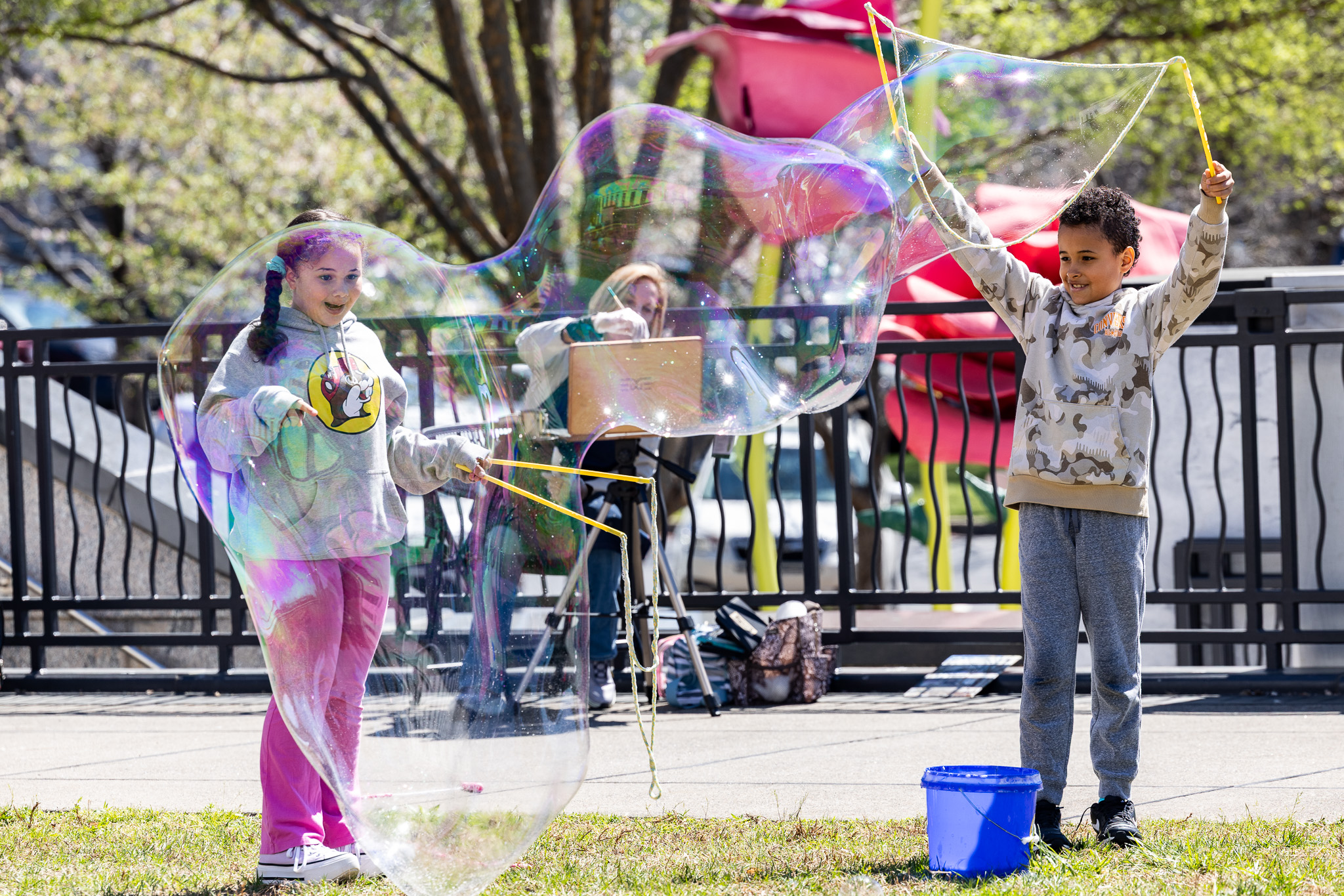 Two children creating large bubbles with wands.
