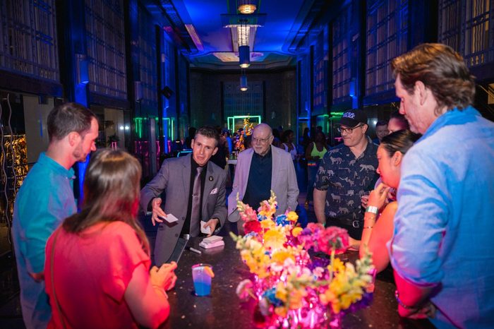 Group of people around a table watching a card magician