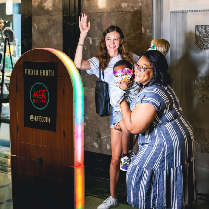 Two women with a child pose for a photo booth.