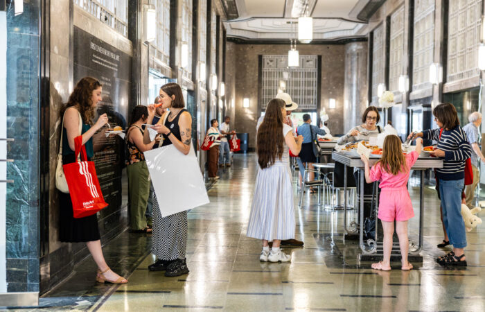 A group of people enjoy light bites in an art deco lobby.
