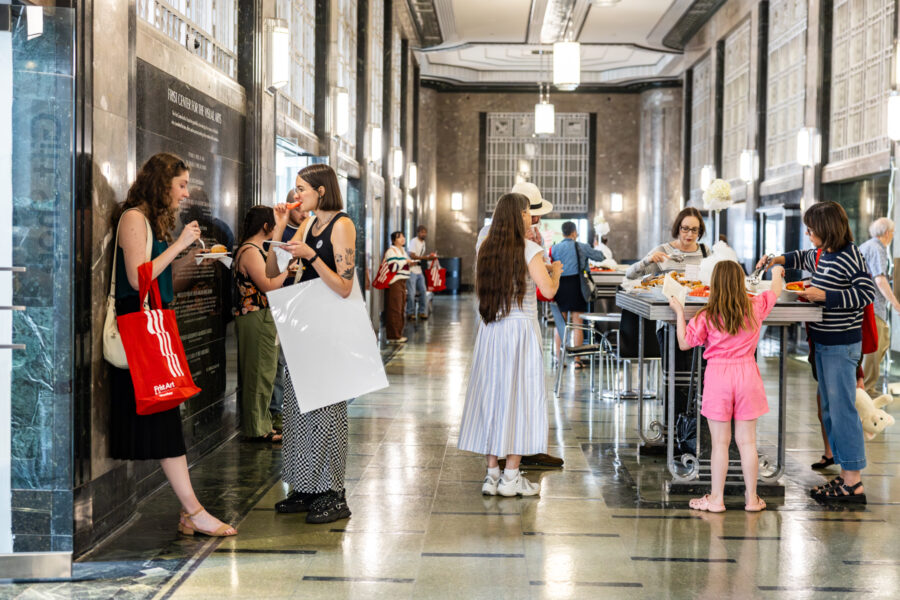 A group of people enjoy light bites in an art deco lobby.