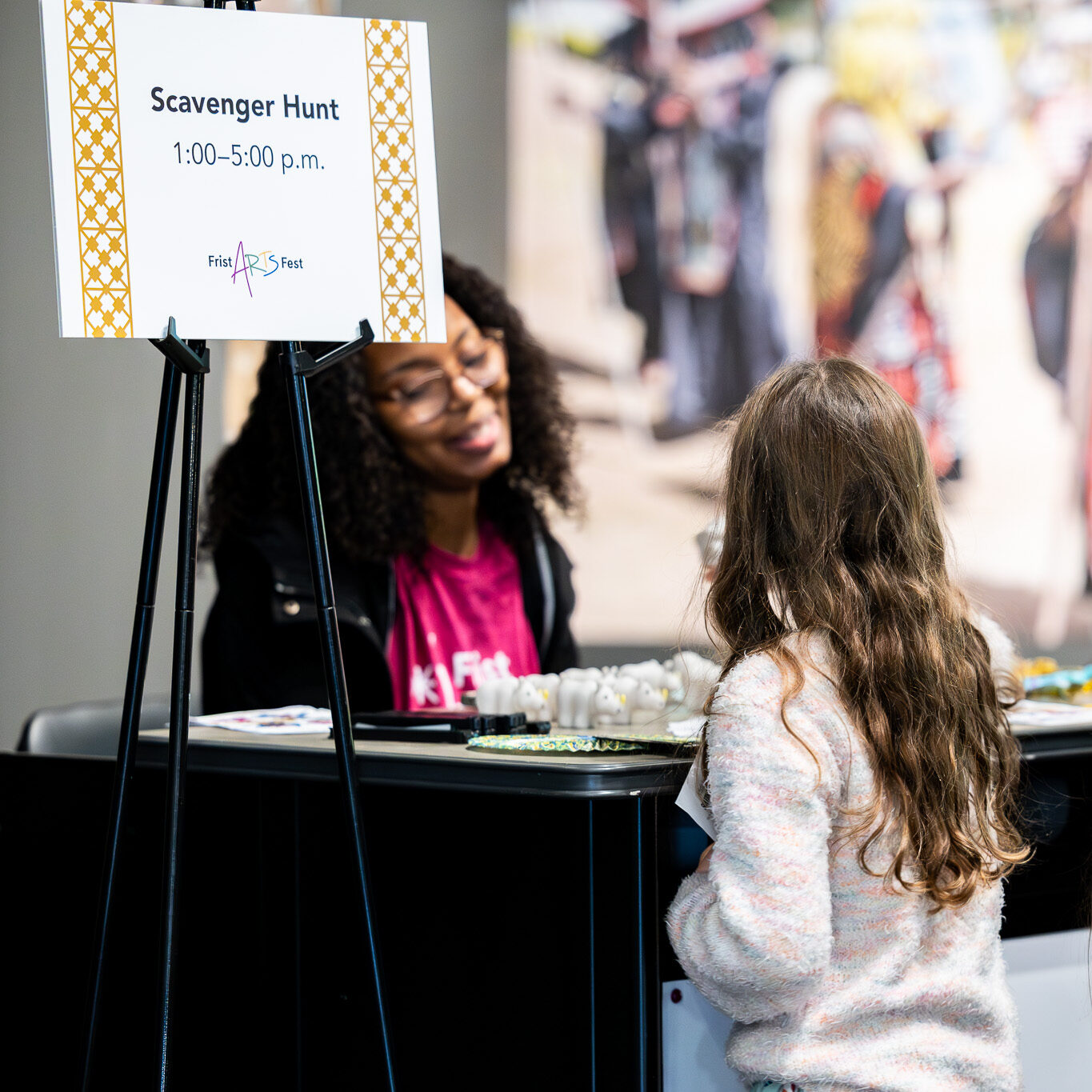 A young girl talks with a woman at a scavenger hunt station.