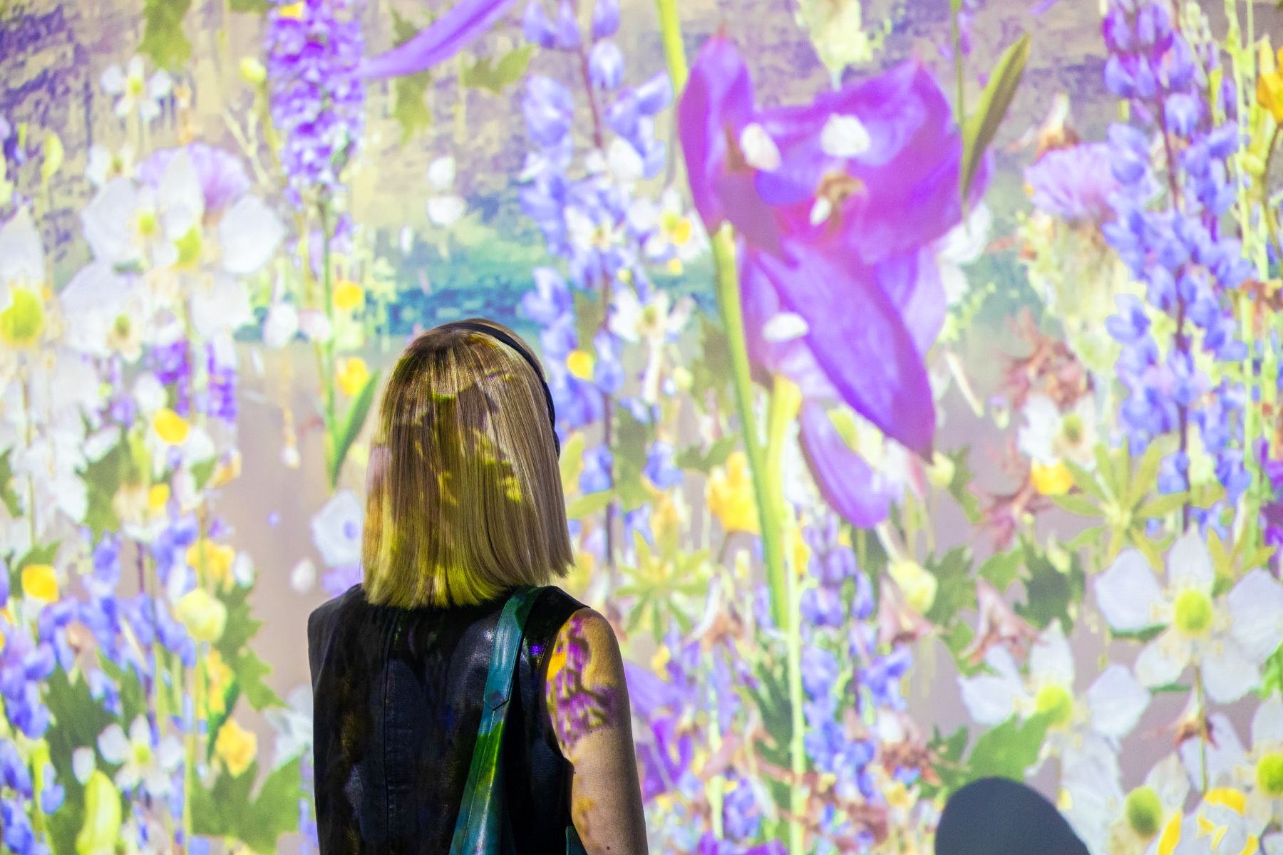 Woman looking at a colorful flower projection