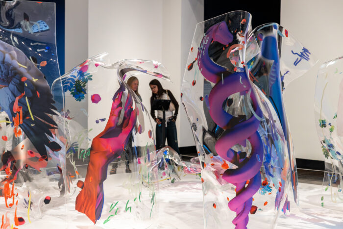 Two people looking at clear sculptures with colorful accents.
