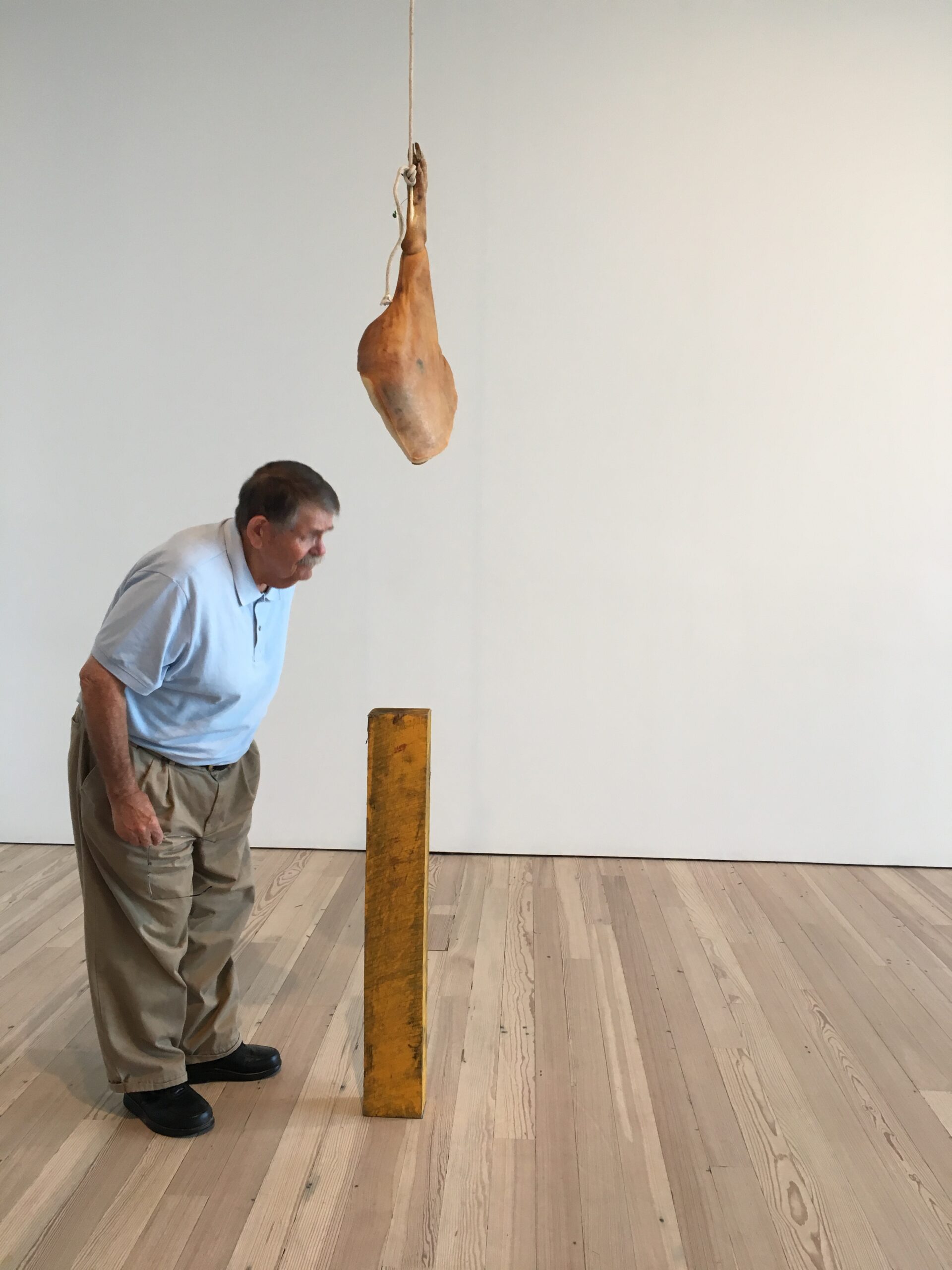Man leaning over to look at a hanging ham and wood beam