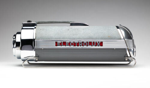 Silver vacuum on thin pegs with a handle on top. “Electrolux” label is in the middle in silver lettering with a red background.