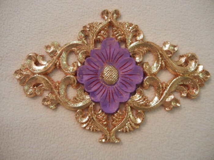 Gold emblem with a light purple floral element in the center