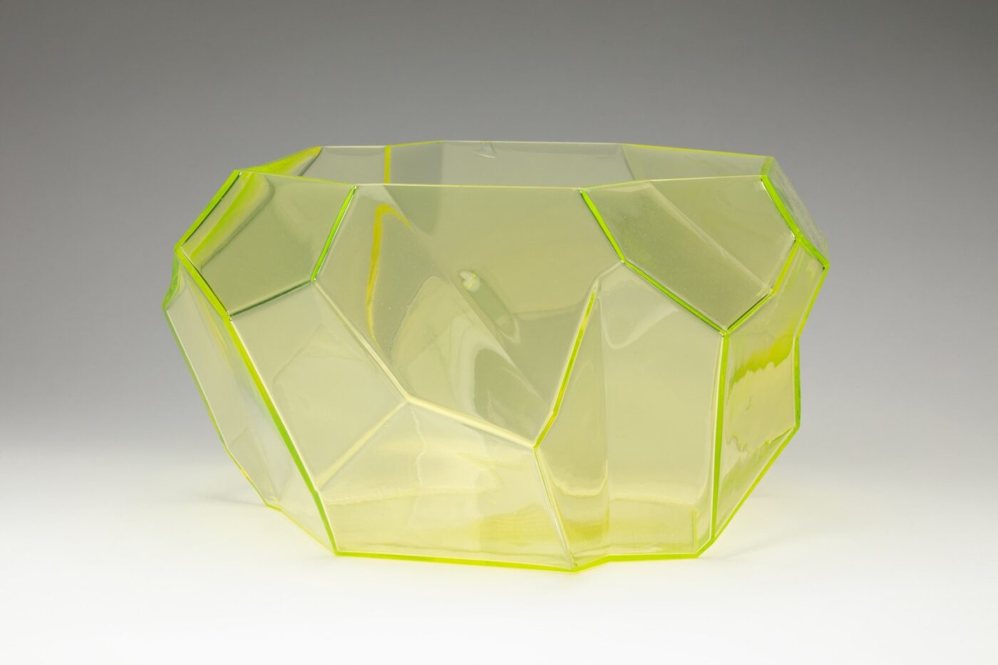 Translucent yellow glass bowl with geometric sides of different shapes and sizes.