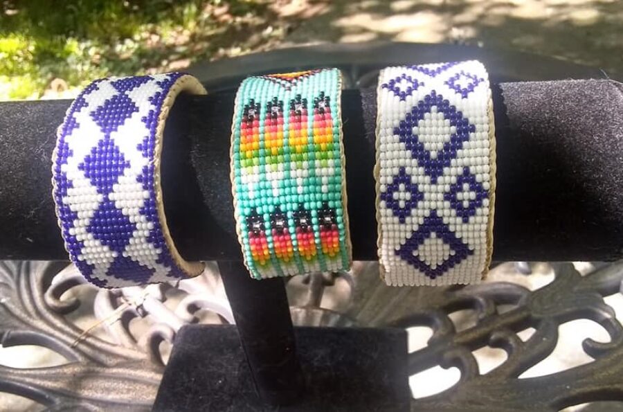Three colorful beaded bracelets hung on a round black velvet jewelry holder