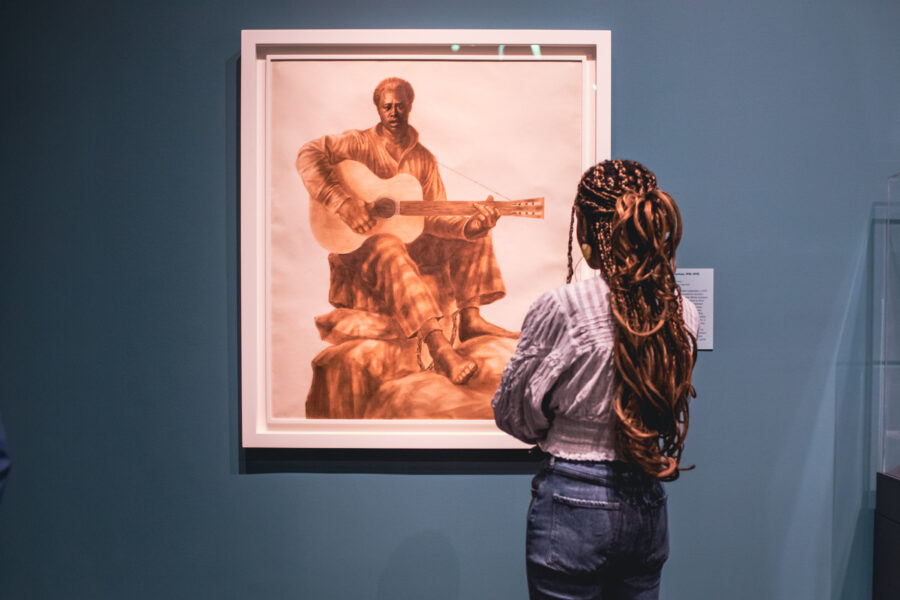 Woman looking at painting of man playing guitar