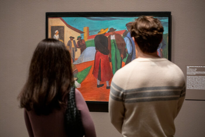 Man and woman standing next to each other looking at a painting