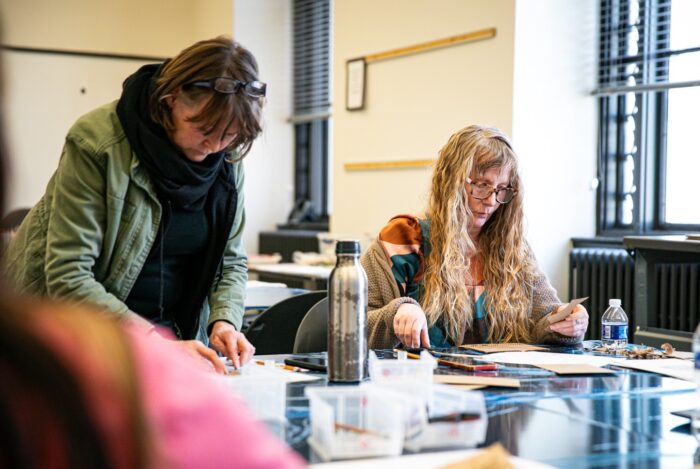 Two women at a table working on an art project