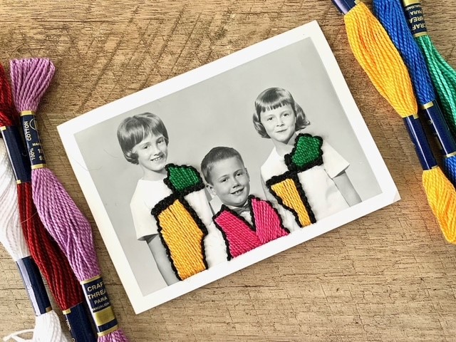 Black and white photograph of three children with yellow, green and pink embroidery on the photo