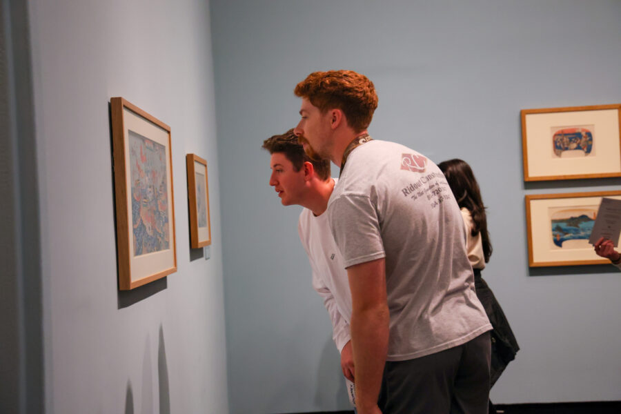 Two men looking closely at a work of art