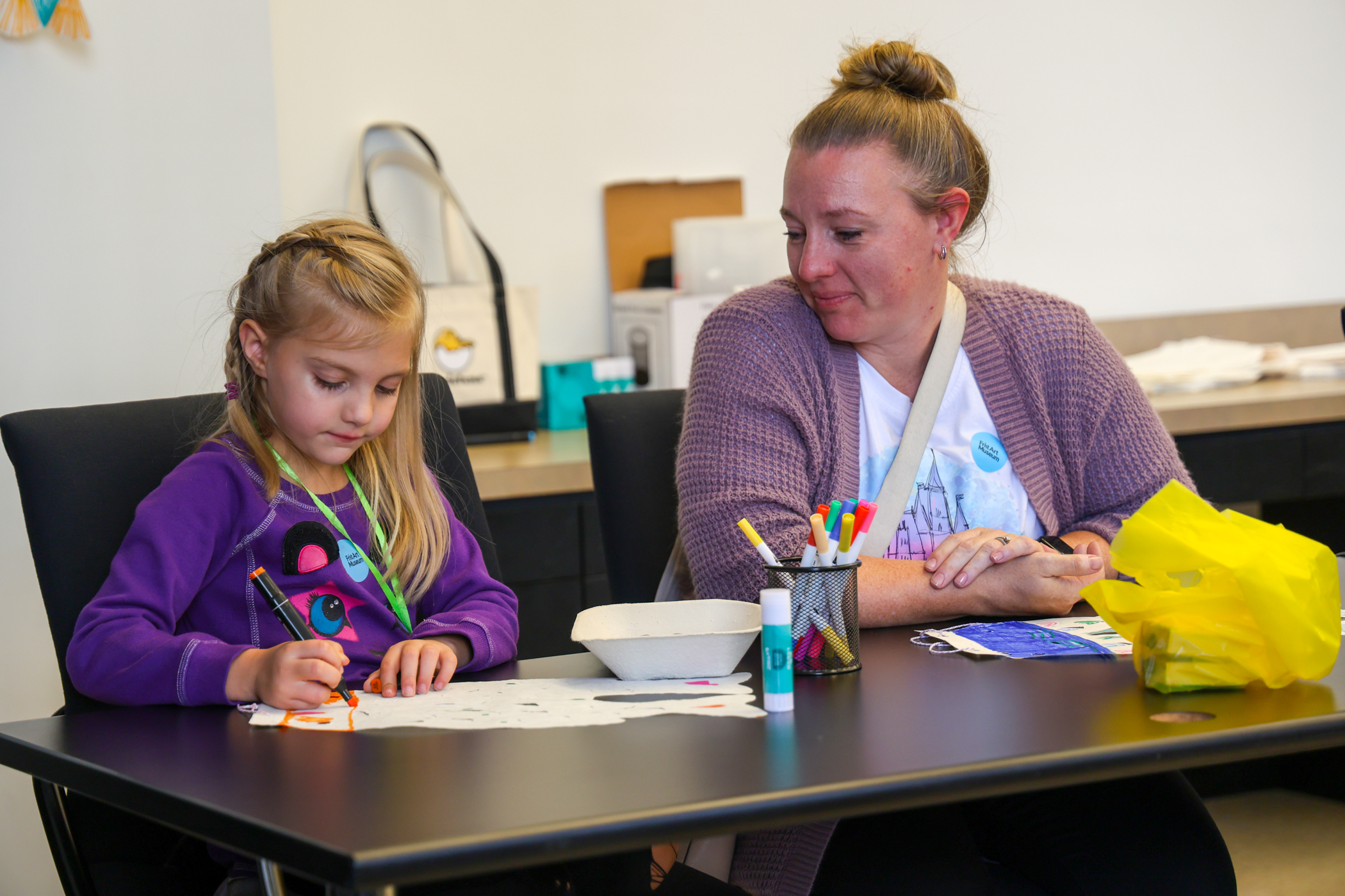 Mother looking on as her daughter works on an art project