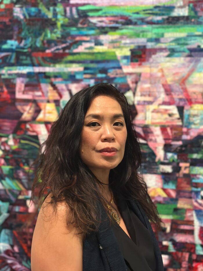 Artist Sisavanh Phouthavong Houghton stands in front of one of her abstract and colorful paintings.