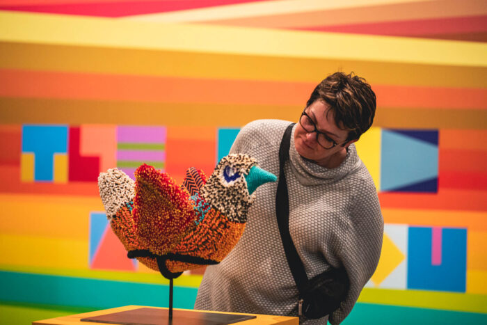 Woman leaning over a beaded bird sculpture to look more closely
