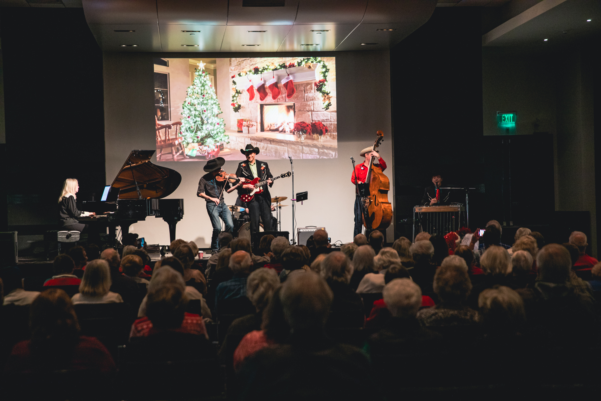 Band on stage playing for a large crowd in an auditorium