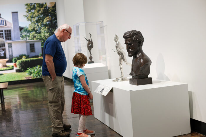 Grand father and grandaughter looking at a sculpture