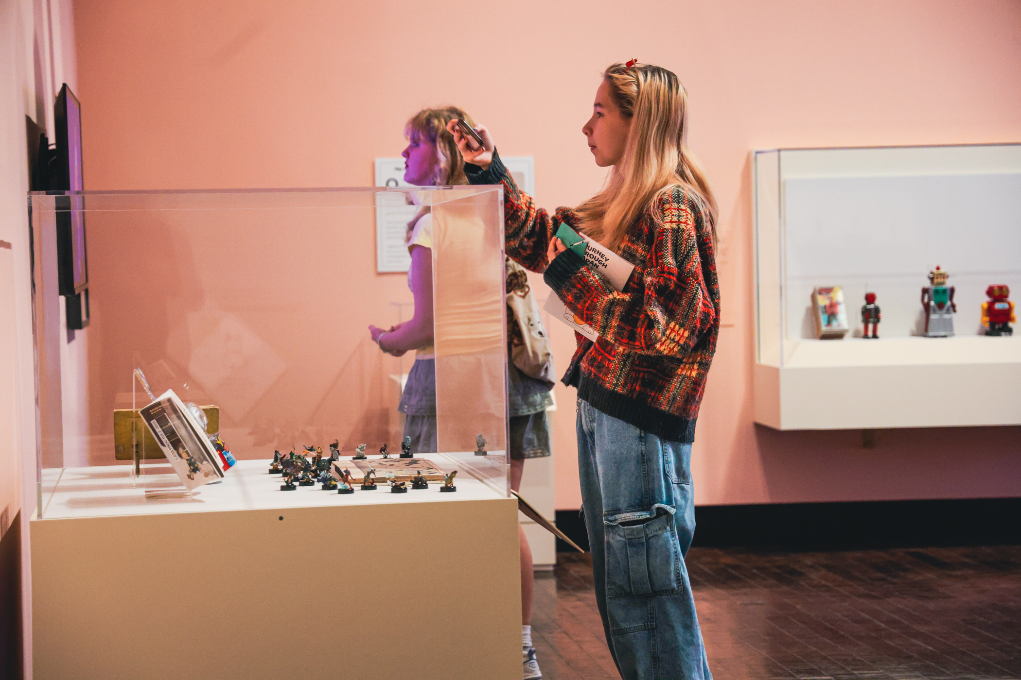 Young woman taking a picture of a work of art in a case