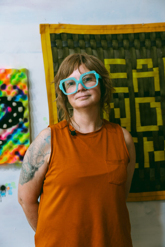 Artist Briena Harmening poses in front of her quilts.
