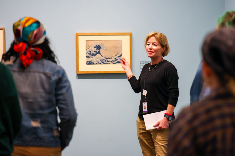 Docent leading a tour and pointing to a work of art