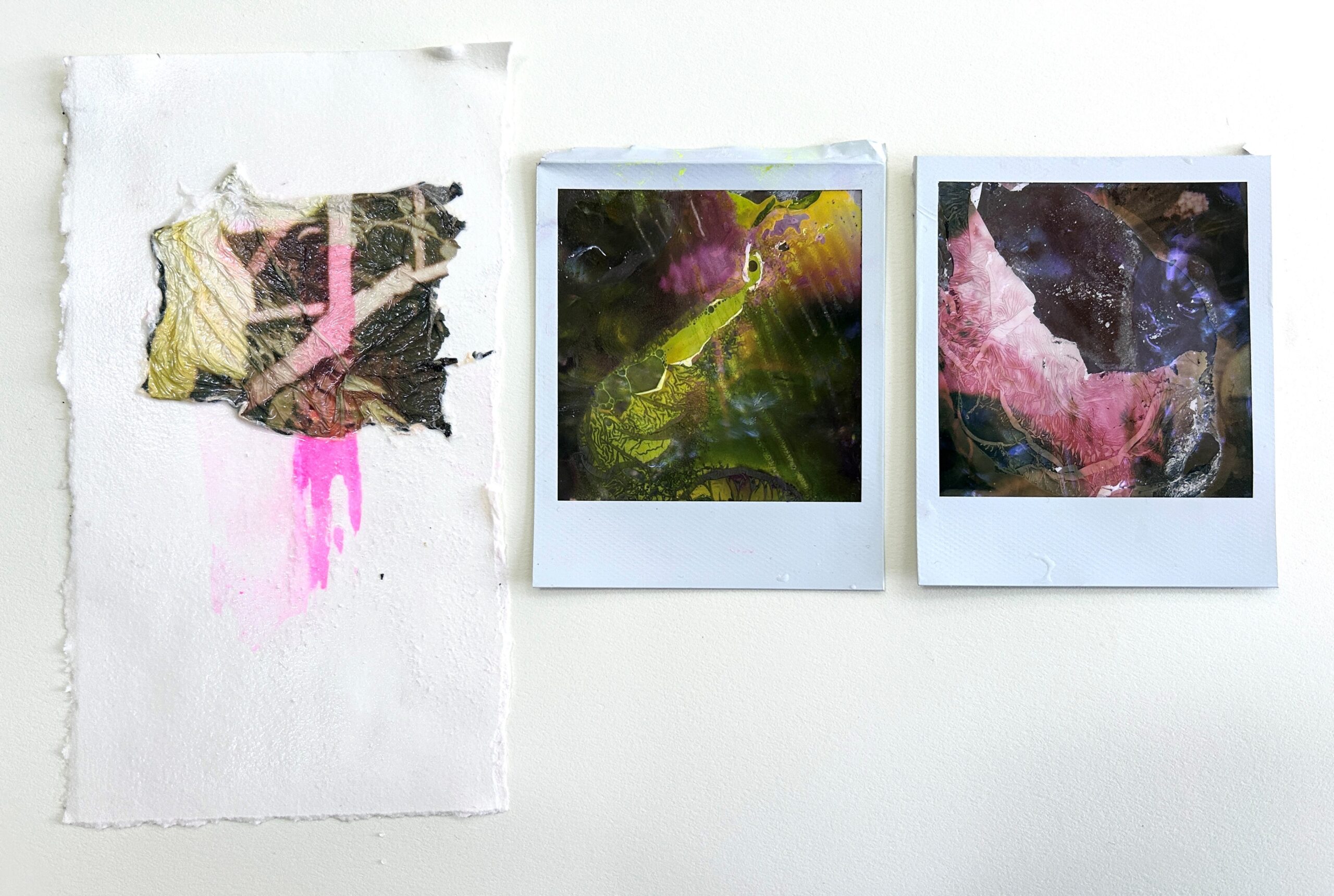 Two polaroids showing abstract images next to a white paper with an imprint of both