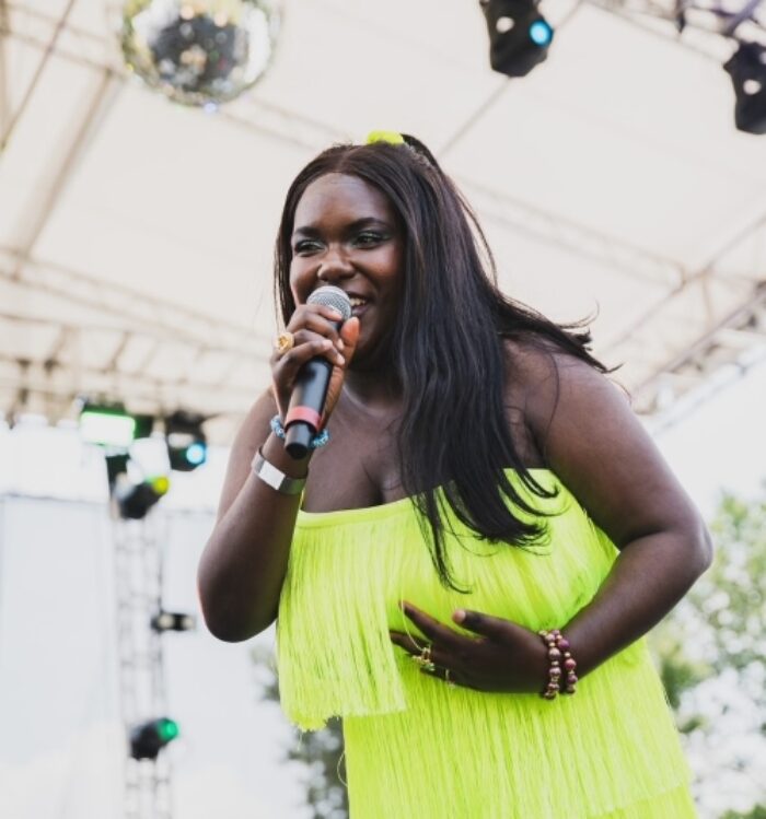Woman in neon yellow dress singing into a microphone