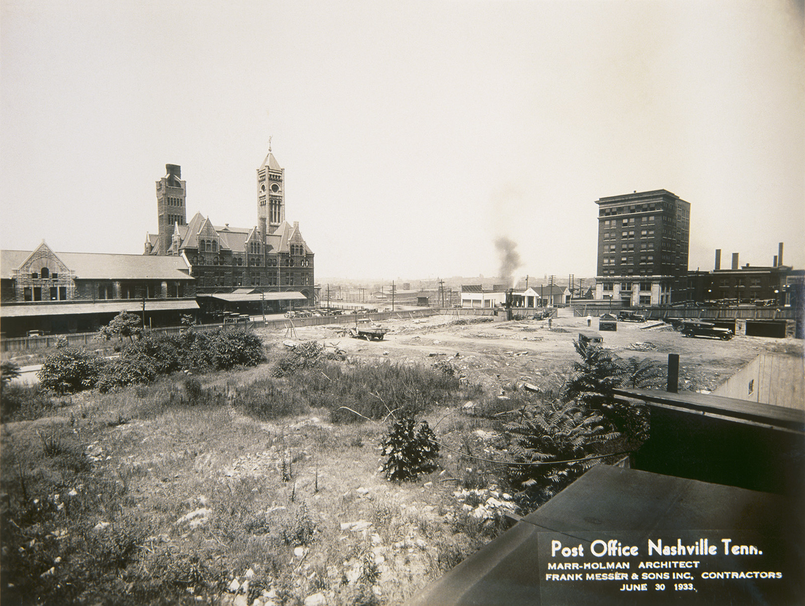 A field –soon to be the site of the city’s main post office. Union Station and the train station’s baggage building and one seven story building appear in the background.