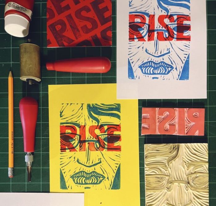 Colorful prints and linocut printmaking supplies laid out on a work surface