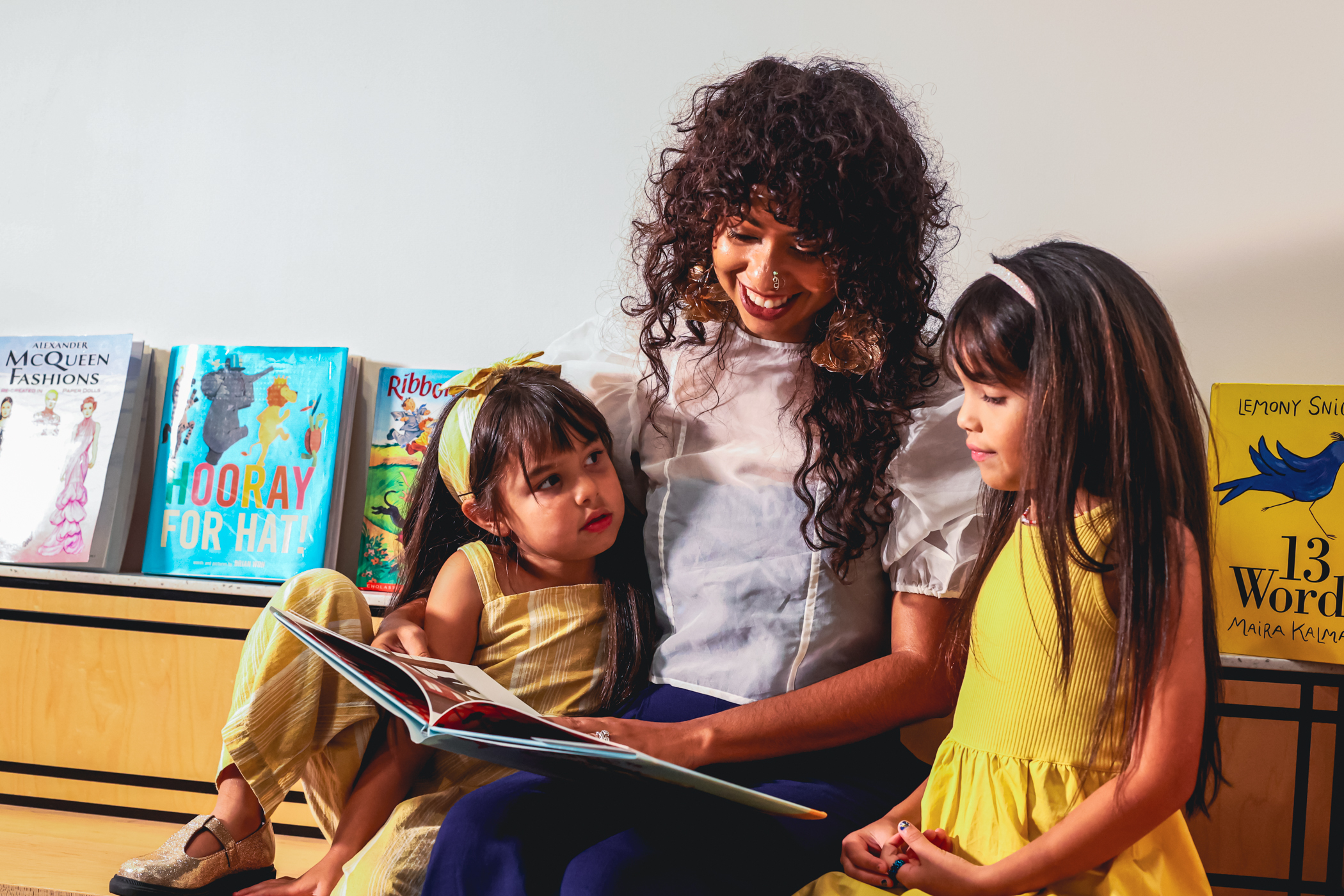 Woman reading a storybook to two young girls.