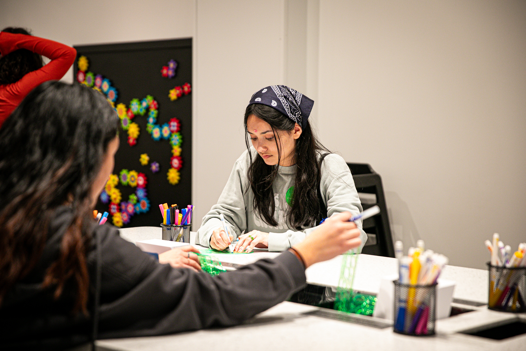 Young girl with bandana on her head working at an art station.