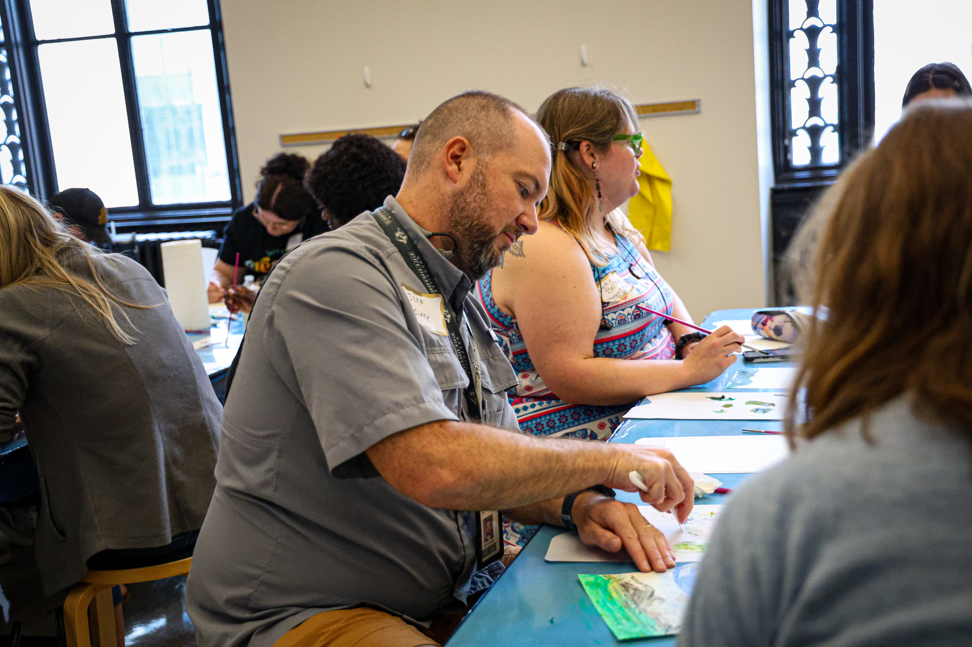 Man and other people sitting at a table, drawing or painting