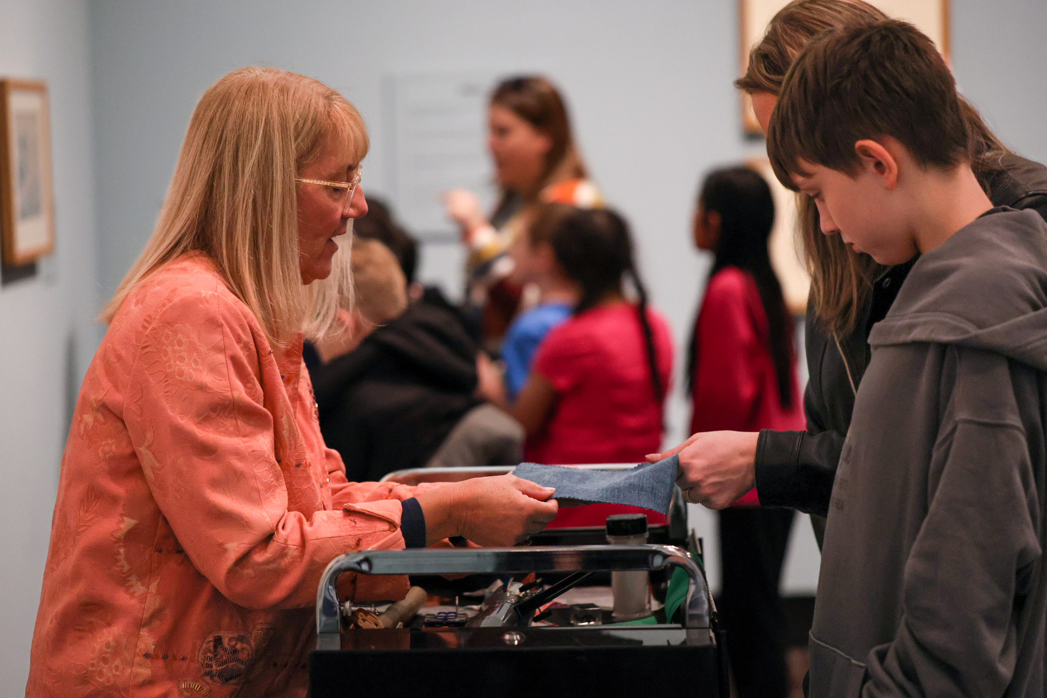 A lady is showing a fabric to the visitors.